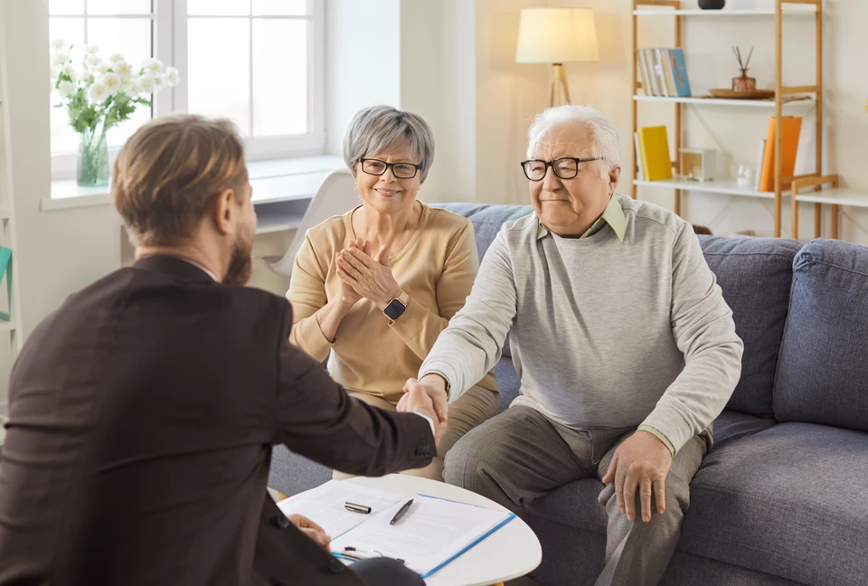 Homme d'affaires en costume sombre et cravate bleue protégeant symboliquement une famille avec ses mains en geste protecteur
