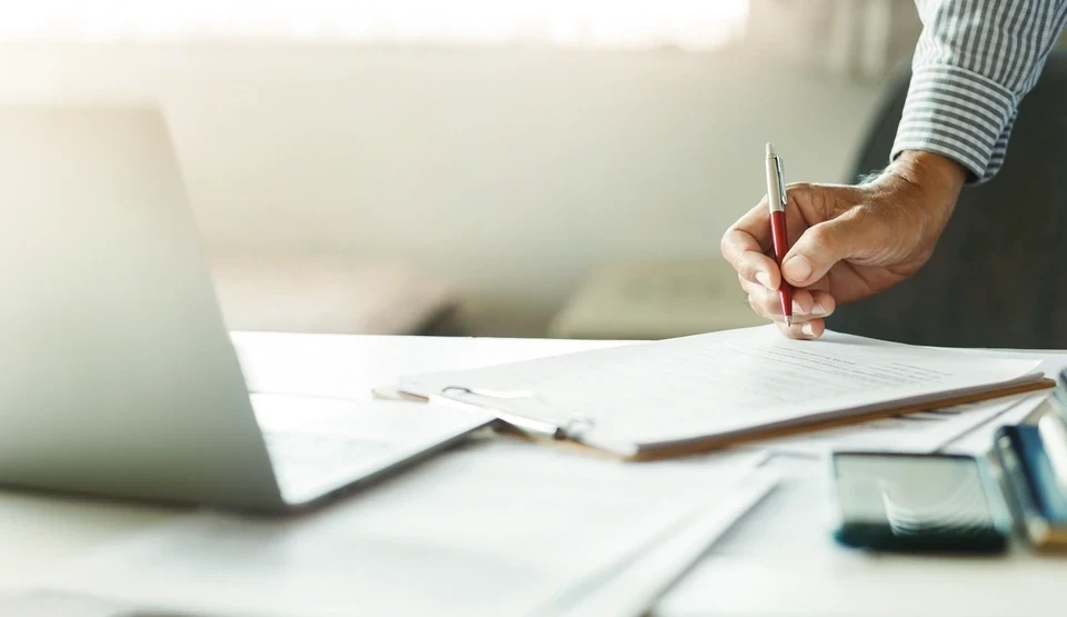 Personne en pull jaune travaillant sur ordinateur portable dans un café ou espace de coworking moderne